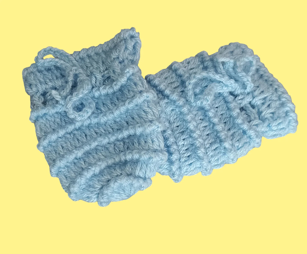 Handmade light blue crochet baby booties on pastel yellow background, Croch'pelotes by Sophie