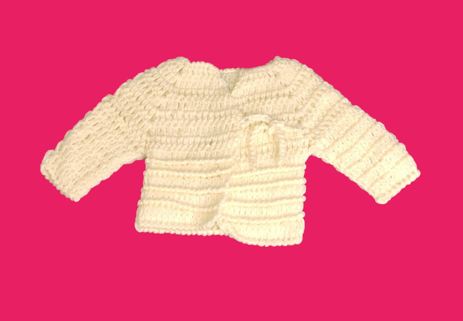 Handmade crochet baby sweater in cream yarn on pink background, Croch'pelotes by Sophie