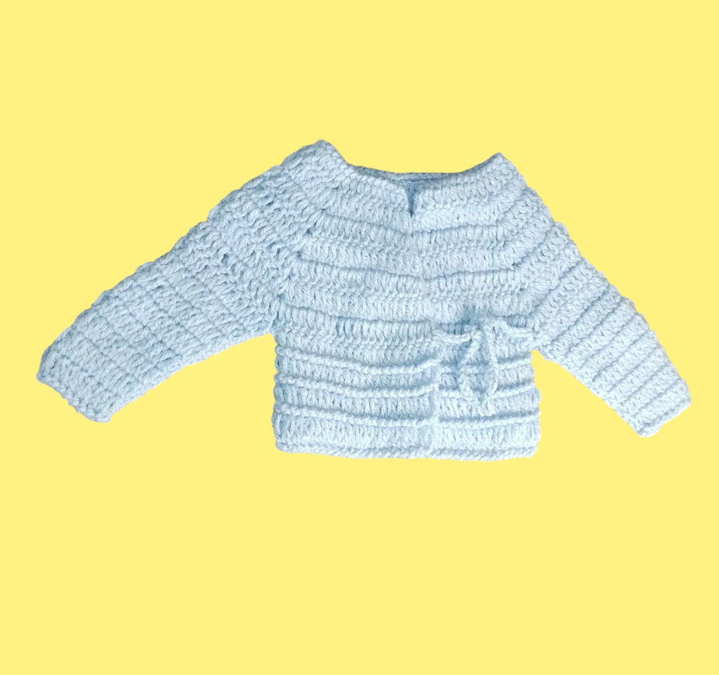 Handmade light blue crochet baby cardigan with textured pattern on yellow background