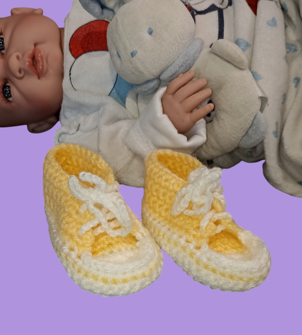 Handmade yellow and white crochet baby booties by Croch'pelotes by Sophie, with doll