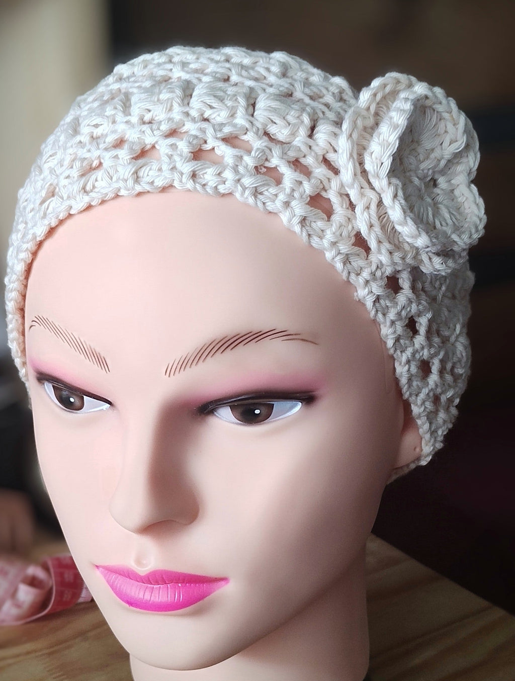 Mannequin wearing handmade crochet headband with flower detail in oat milk color