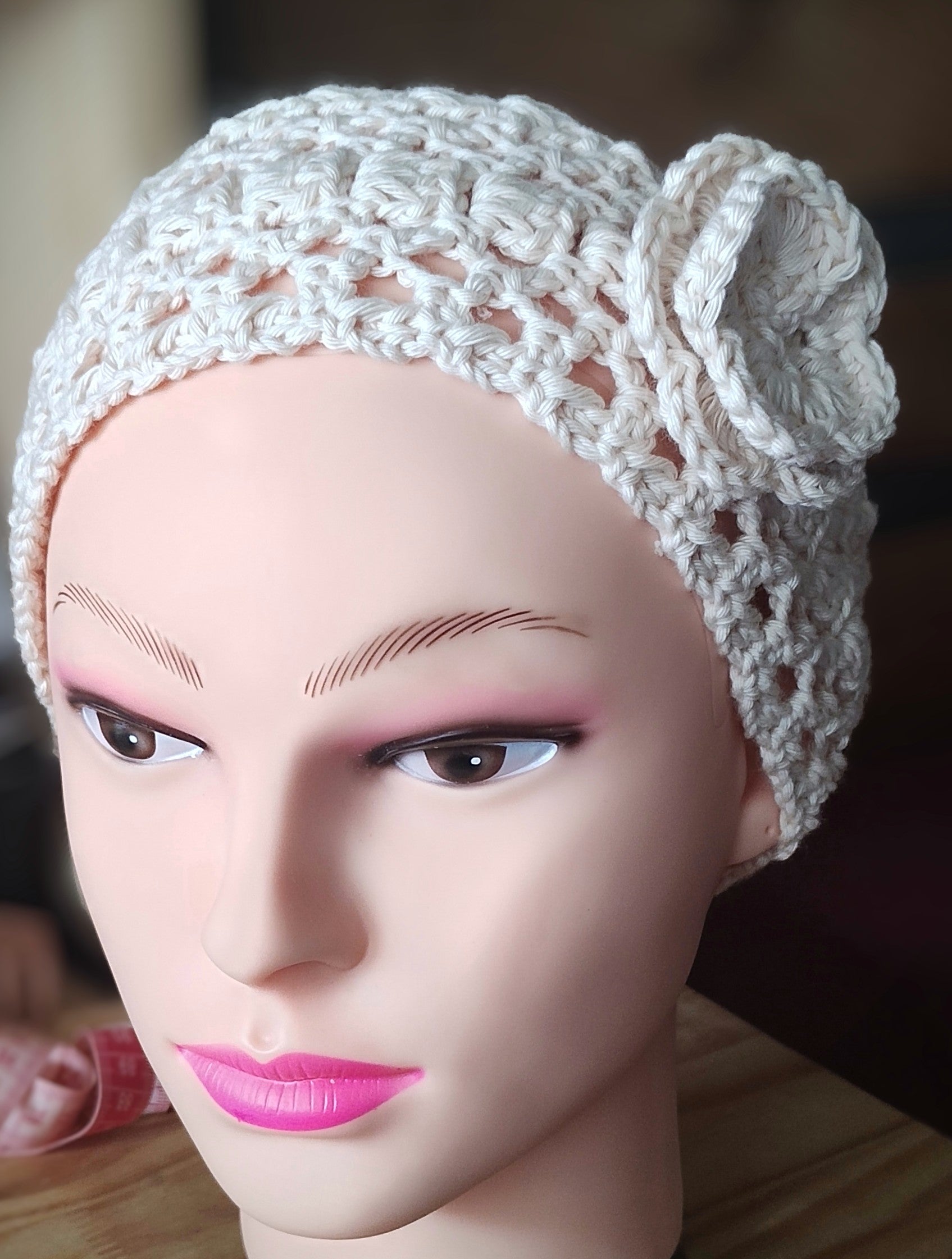 Mannequin wearing handmade crochet headband with flower detail in oat milk color